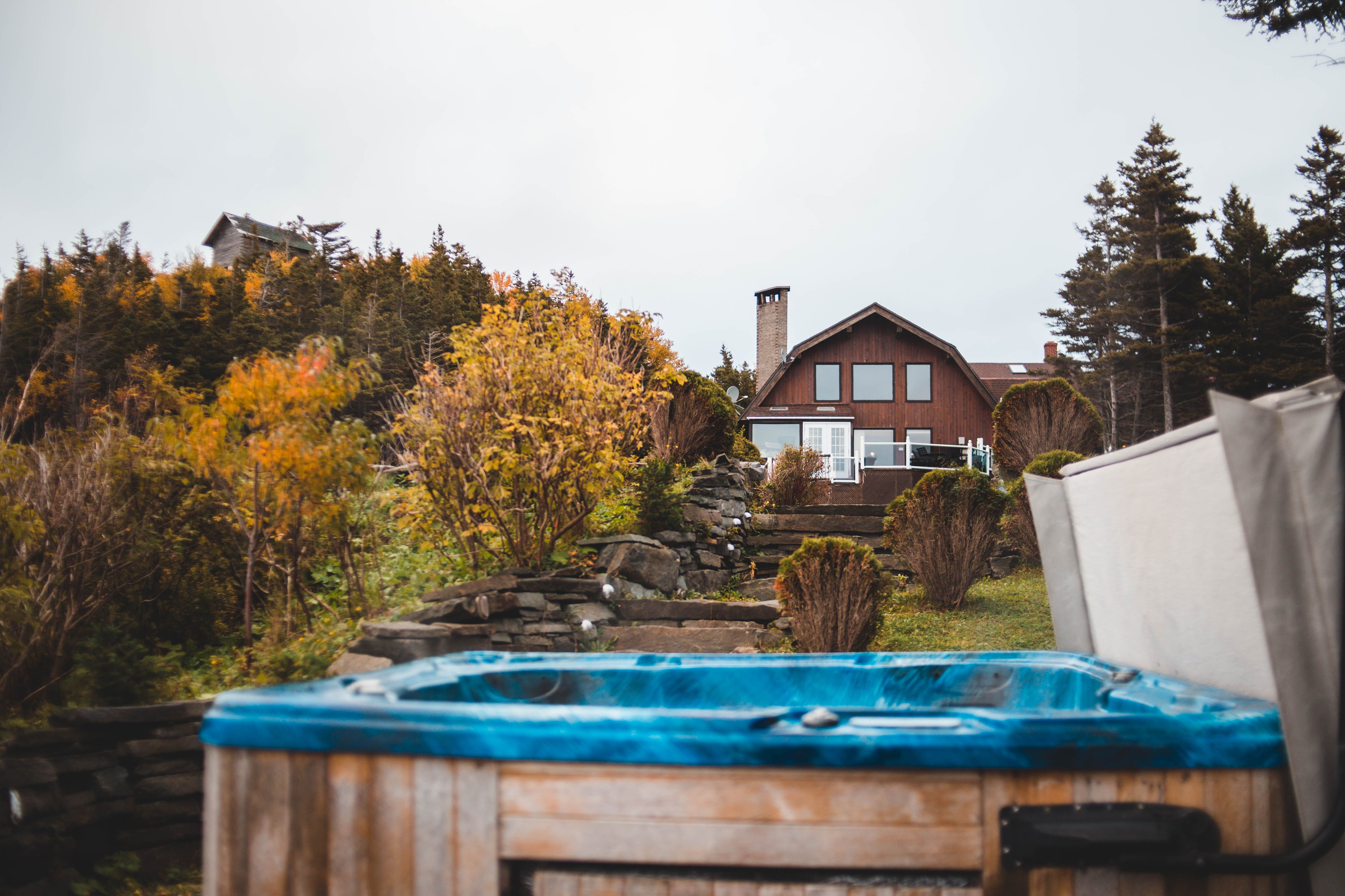 Countryside home surrounded by colorful autumn foliage with a hot tub in the foreground