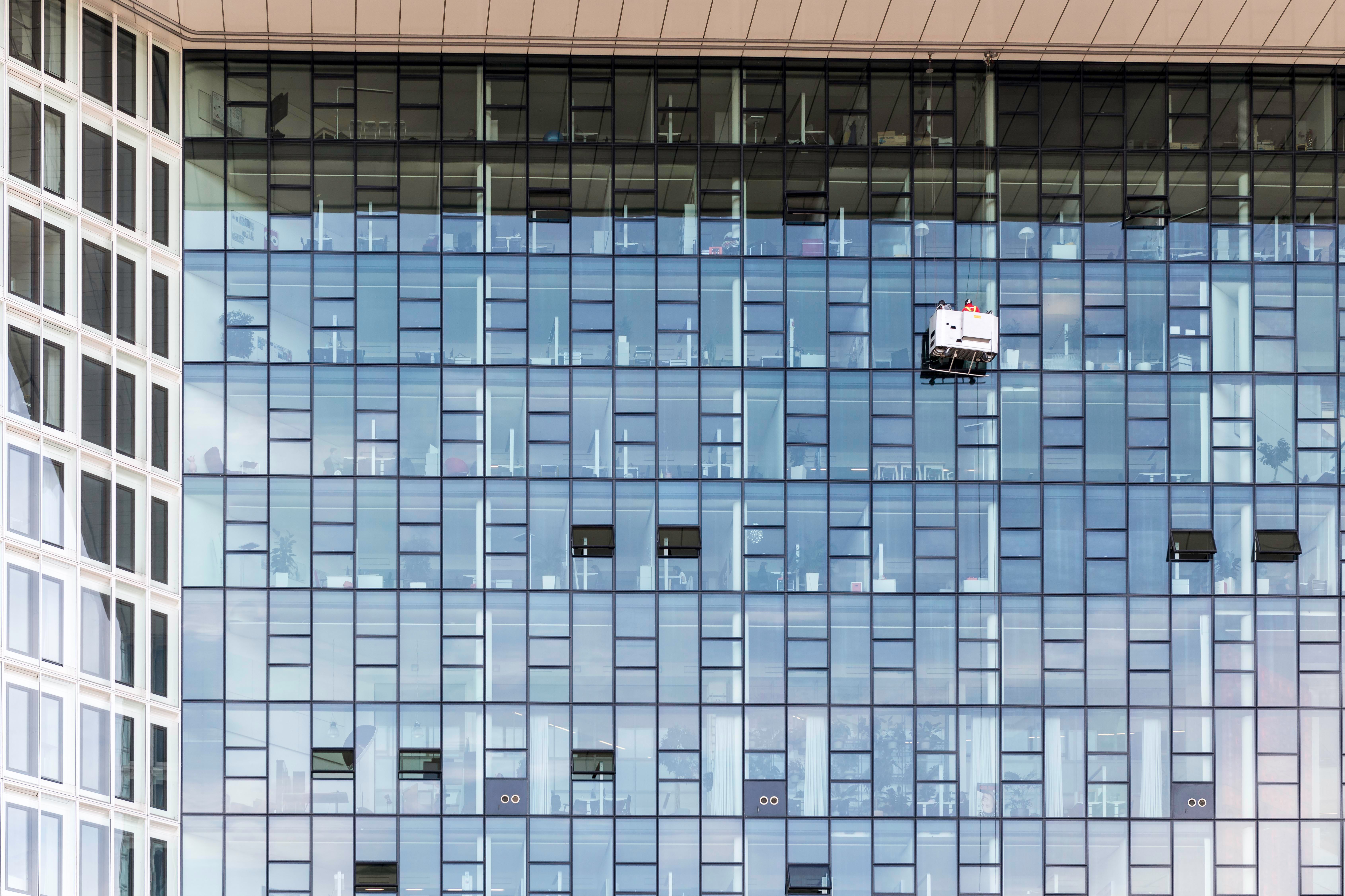 High-rise glass office building exterior with window cleaners working at height