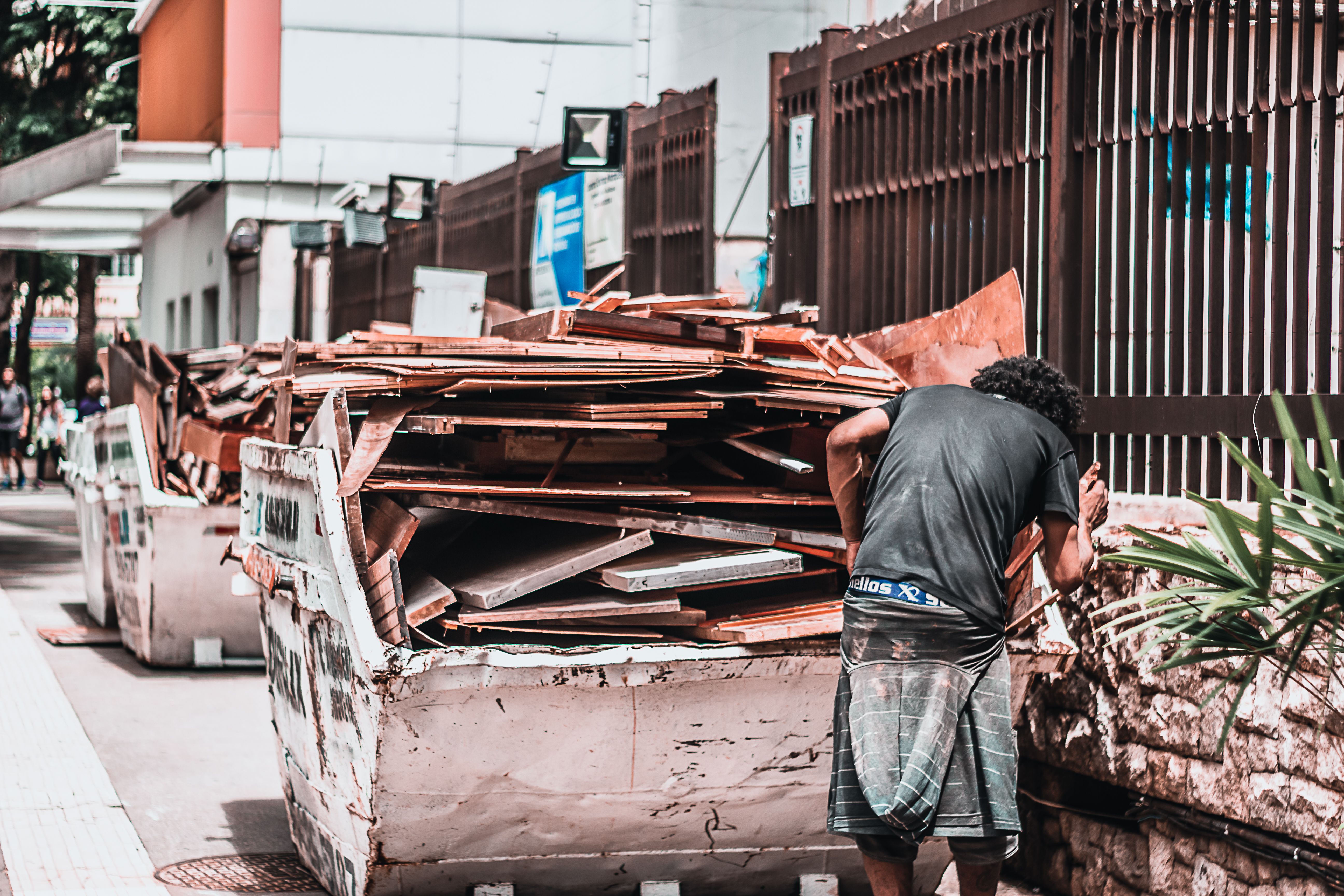 Worker collecting construction debris from a waste container during a property debris removal
