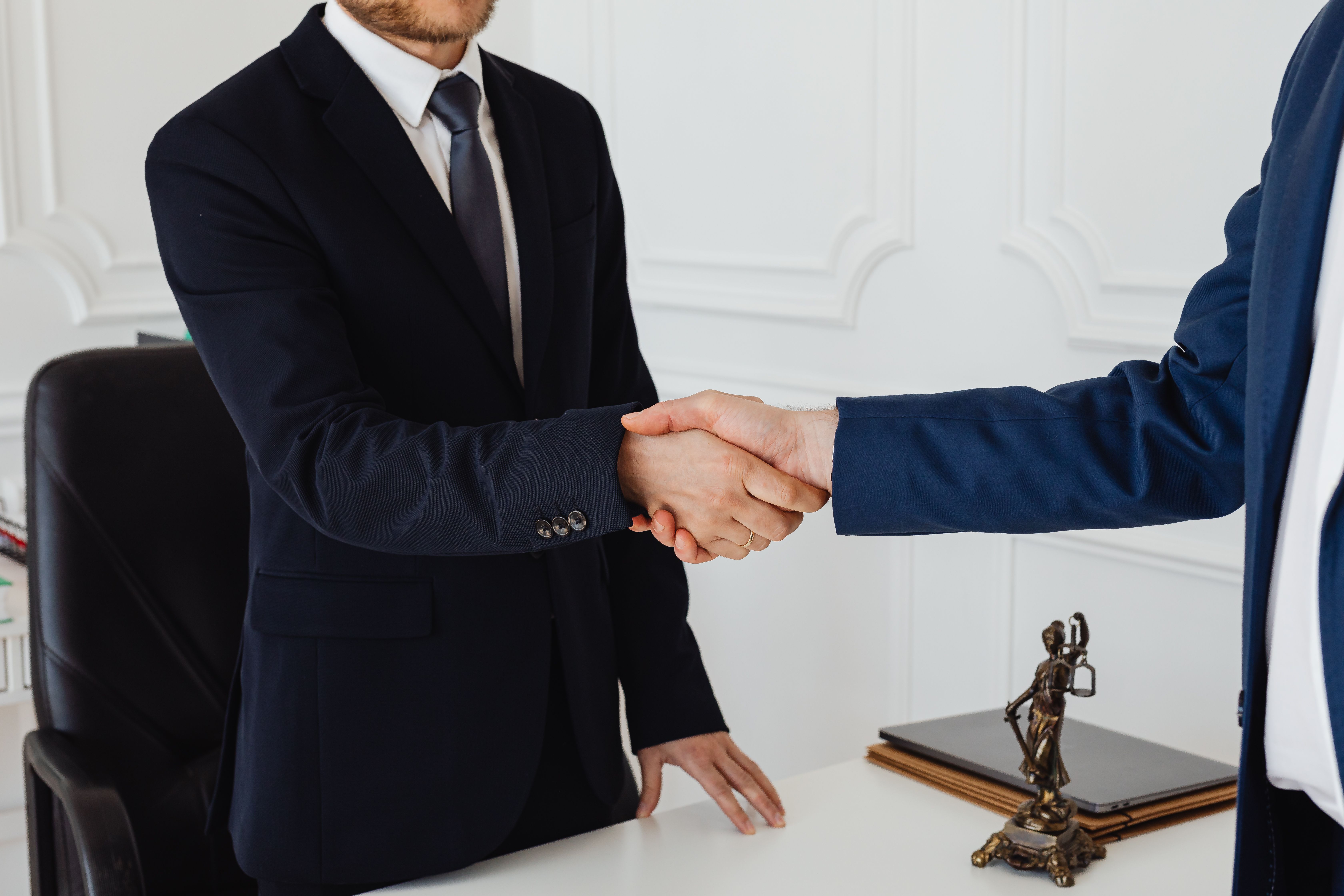 Two people shaking hands in a formal office after reaching a divorce mediation agreement