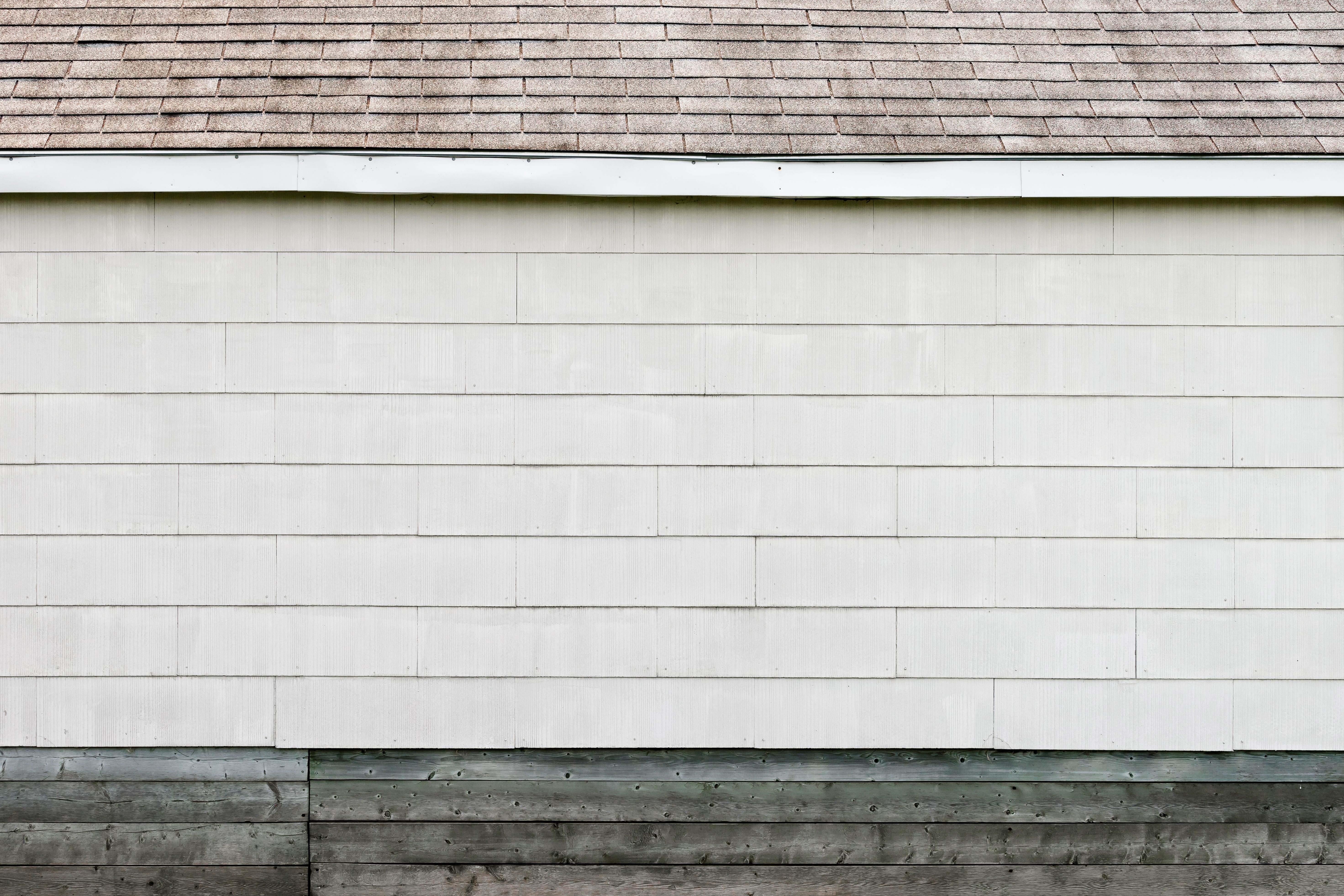 Clean house exterior with white siding and shingled roof after soft washing