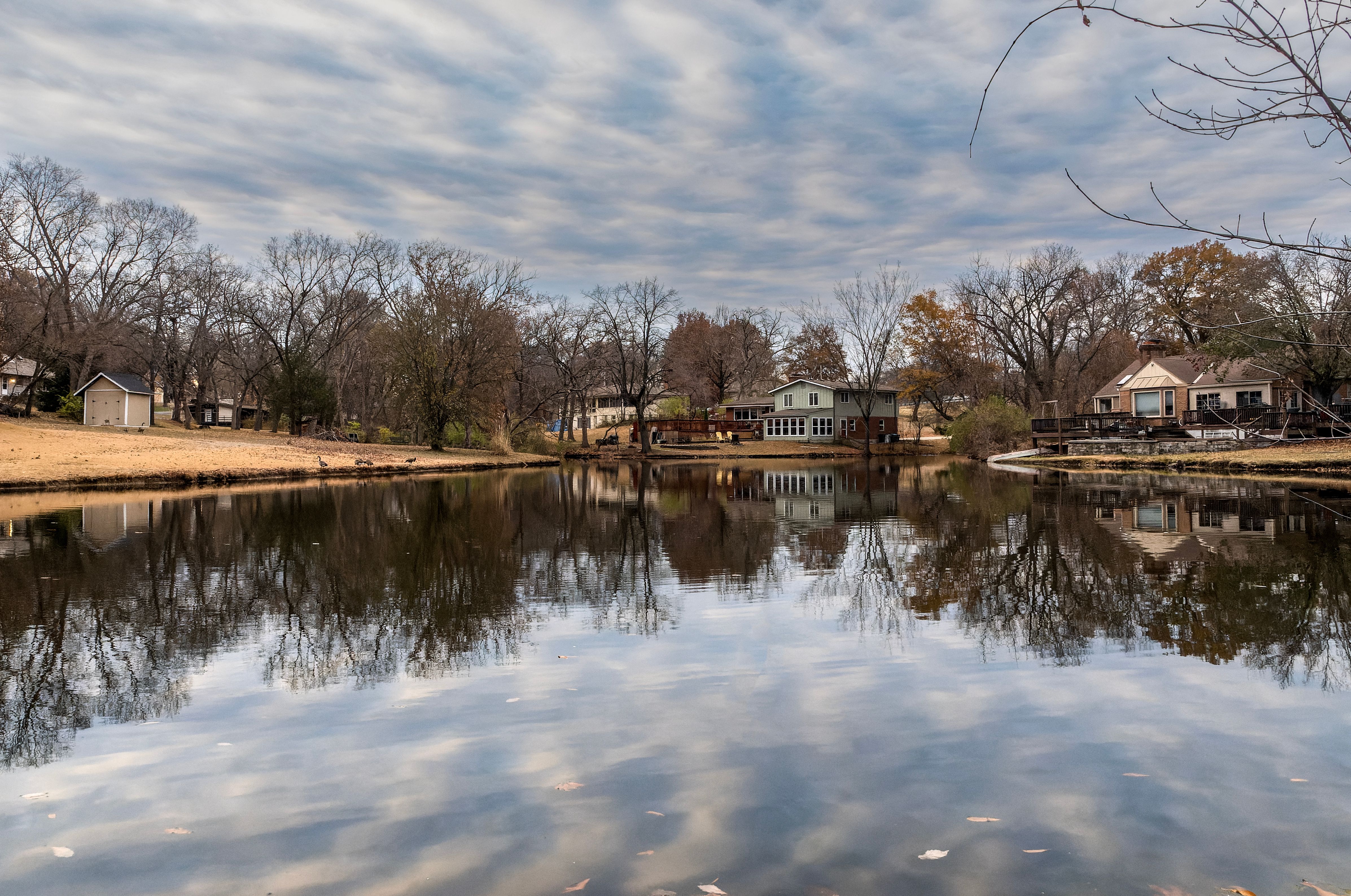 Lakeside homes reflecting on tranquil water in Platte Woods, Missouri