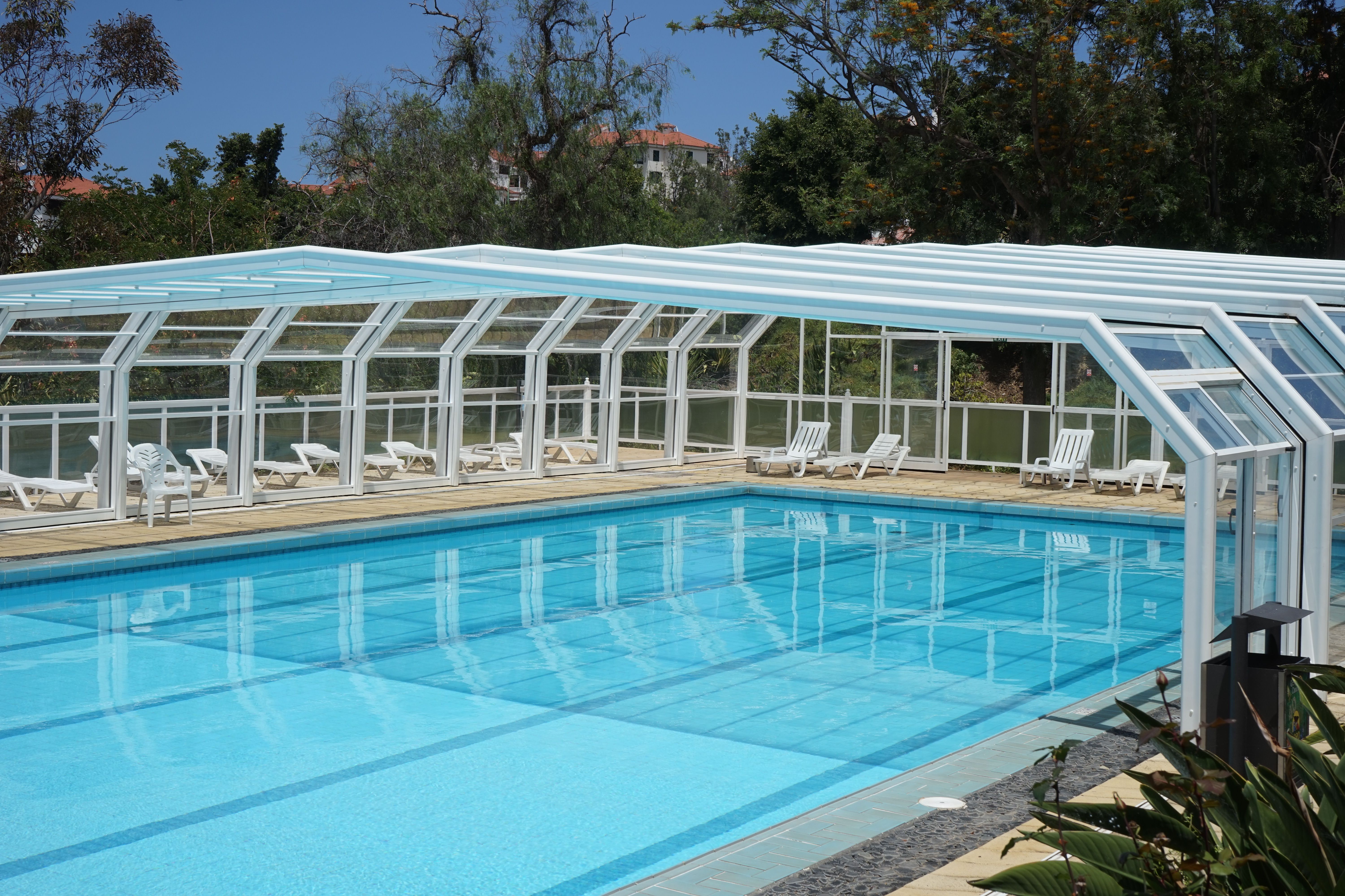 Serene outdoor swimming pool fitted with a modern safety cover surrounded by lush greenery