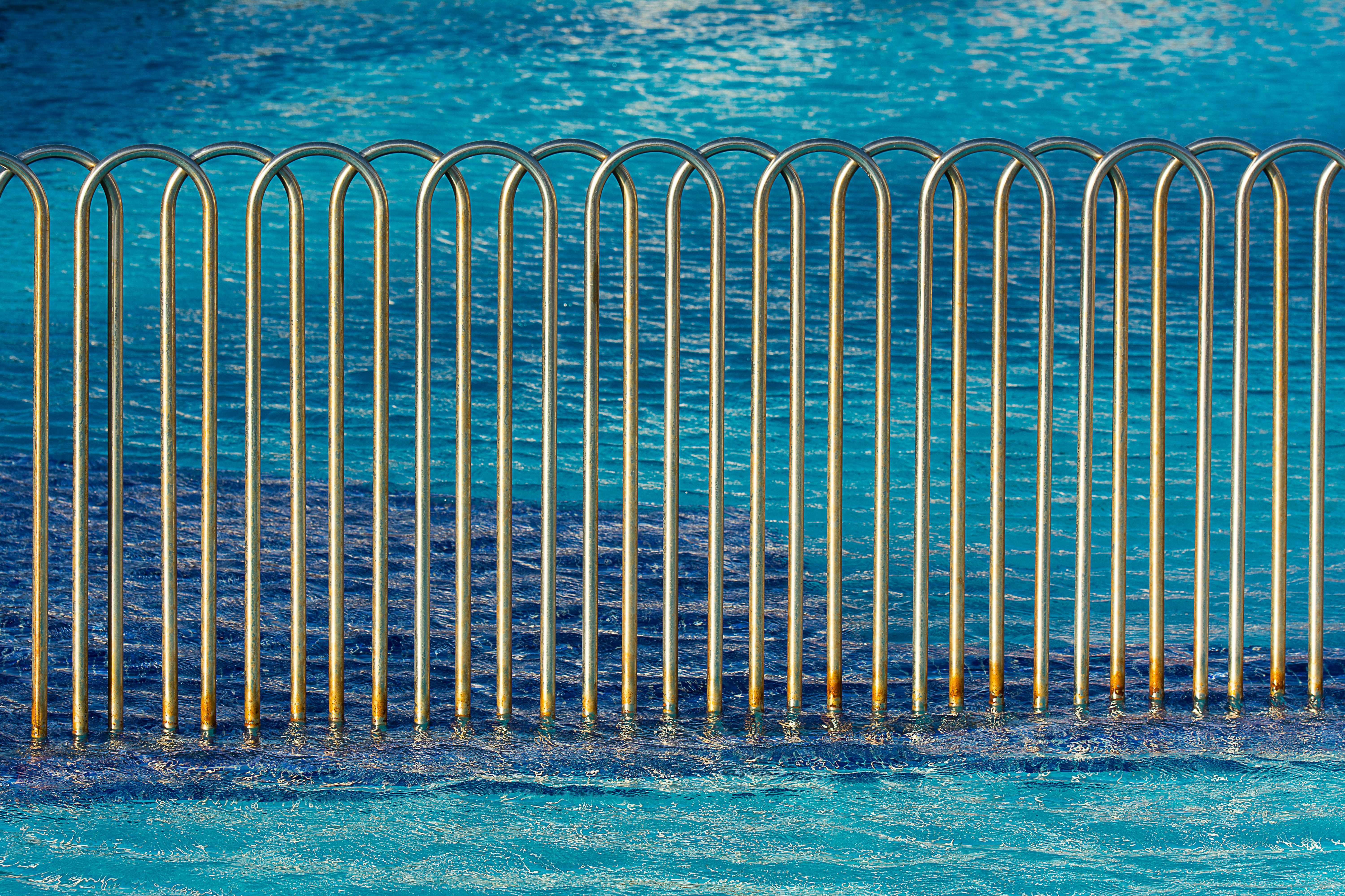 Modern safety fence surrounding a clear blue swimming pool