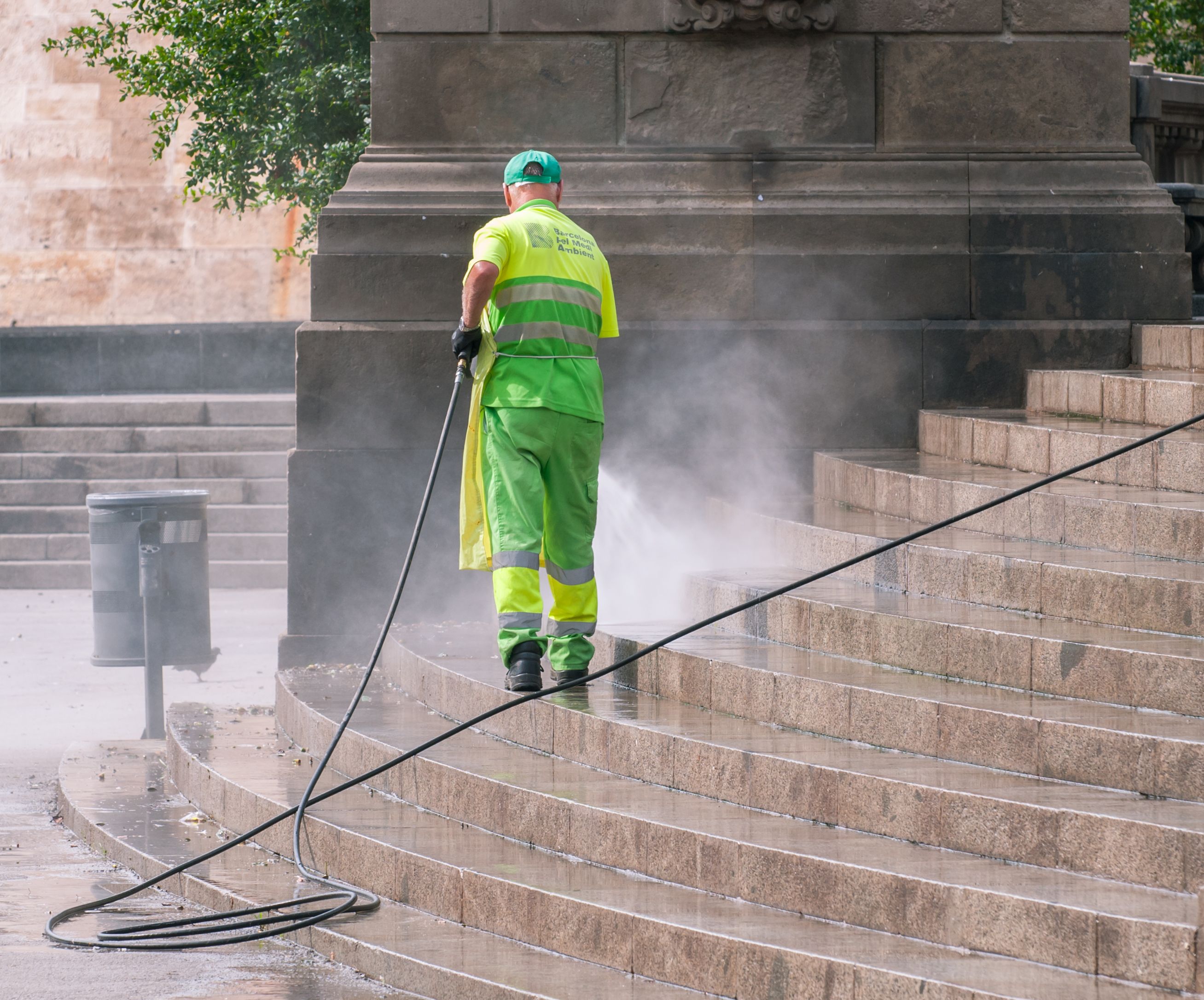 Worker power washing stone steps and entryway with a pressure washer