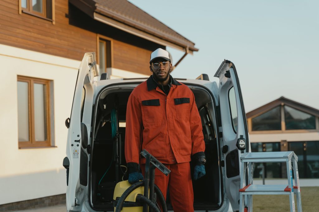 Professional power washing technician in workwear standing with cleaning equipment and service van