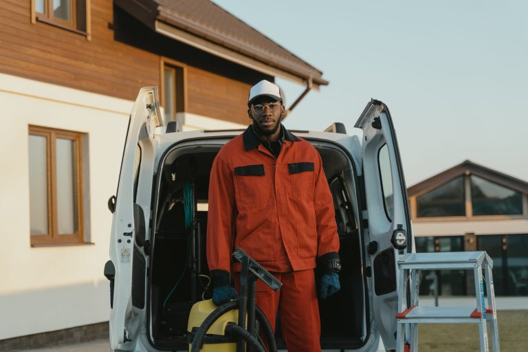 Professional power washing technician in workwear standing with cleaning equipment and service van